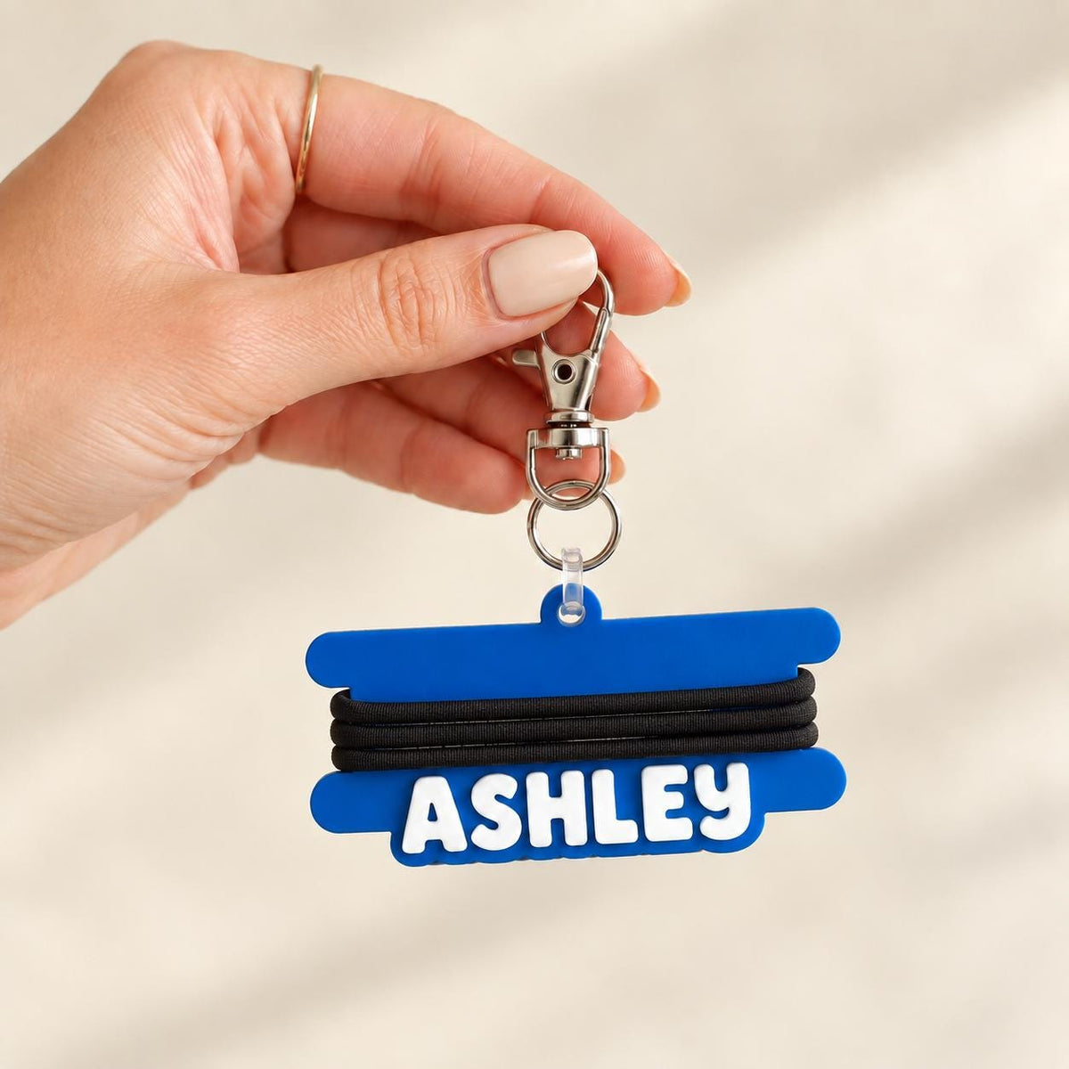 Personalized name keychain hair tie holder clipped to a bag